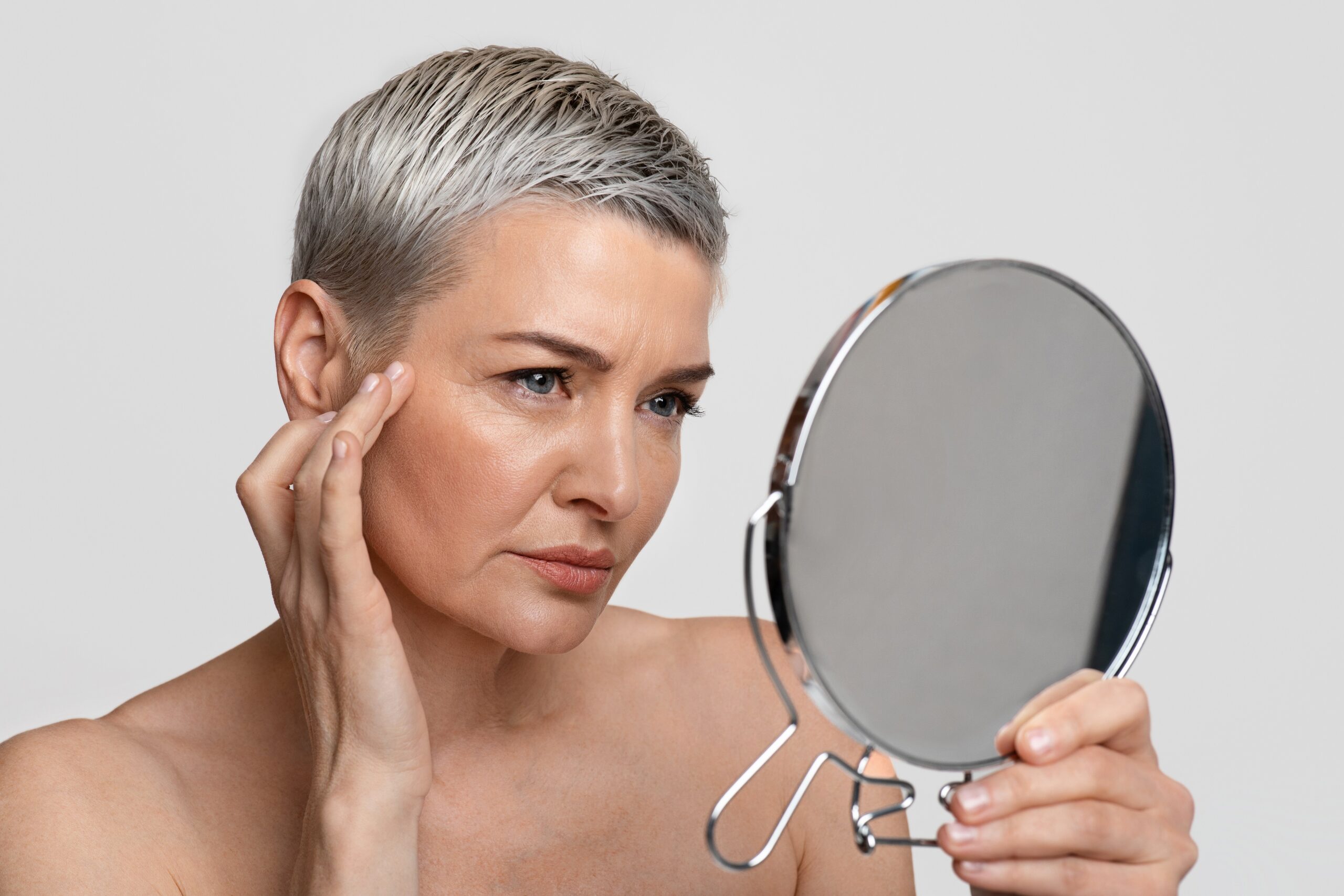 A woman looking at the mirror to see the effects of reversing sun damage.